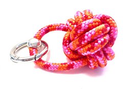 Colorful paracord keychain in shades of orange, pink, and red. Features a decorative knot design.