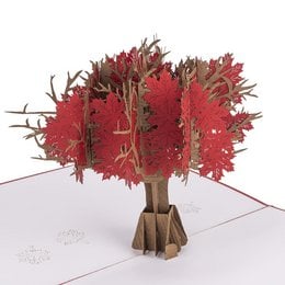 A red maple tree pop-up card with intricate white silhouette designs of maple leaves and branches.