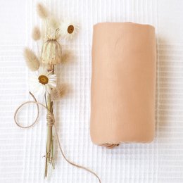 Soft, tan-colored swaddle blanket made of natural materials, suitable for wrapping and comforting newborns.