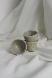 Glossy handmade ceramic cups in a minimalist, modern design. Features a simple, curved shape with a neutral color palette.