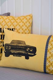  Yellow pillow cover with a vintage car graphic and a patterned border.