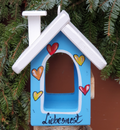  Colorful wooden bird feeder house with heart designs, white roof, blue and green variants, "Liebenest" text, mountain hut style.