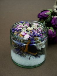 Holistic protection and anchorage supplement in glass jars of varying sizes, containing dried purple flowers and herbs.