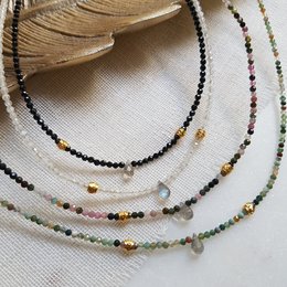 Necklace with multicolored gemstone beads including agate, moonstone, spinel, and tourmaline. The necklace features a delicate, layered design with a variety of bead shapes and colors.