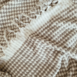 Soft, plush taupe-colored bath towel with a textured pom-pom design, available in two sizes.