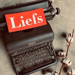 A vintage typewriter with the word "Liefs" displayed prominently on the paper. The typewriter appears to be an old-fashioned model, suggesting a nostalgic or sentimental theme.