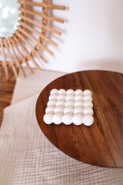  Round, white bubble coasters made of ceramic material, suitable for use on a wooden table.