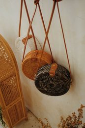 Woven shoulder bag in brown, black, and white colors with a unique basket-like design.