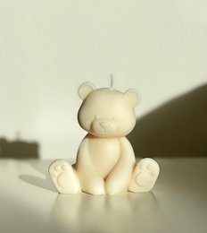 Soft, plush teddy bear-shaped candle in a neutral color. Ideal for creating a cozy, relaxing ambiance in any room.