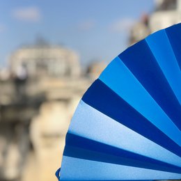  Light blue opaque hand fan with a radial pattern design.