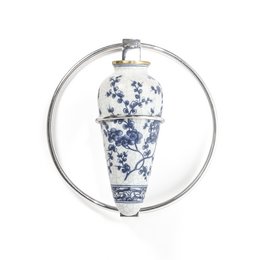 Tall, cylindrical blue and white ceramic vase with floral pattern, suspended in a metal ring.