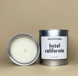 Tall, round, white scented candle in a silver tin with the label "Hotel California".