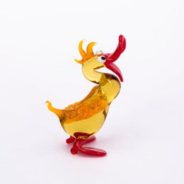A decorative glass duck figurine with a yellow body, red beak, and red feet. The duck appears to be in a playful, animated pose.