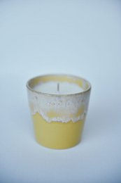  Yellow scented candle in a glass container with a white wax top.