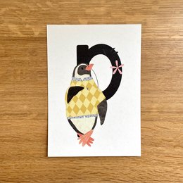 Colorful illustrated card featuring a penguin in a yellow and black argyle pattern. The card is part of a series with letters of the alphabet.