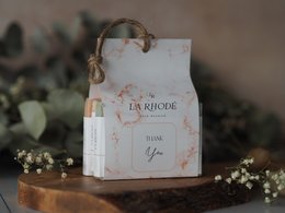 A white gift box with a thank you message, decorated with floral elements and a rope handle. The gift box appears to be part of a beauty or spa gift set, potentially containing items like soaps or lotions.