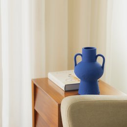  Handmade ceramic vase in a vibrant blue color, with a unique rounded shape and two handles. Suitable for use as a decorative accent piece or small flower vase.