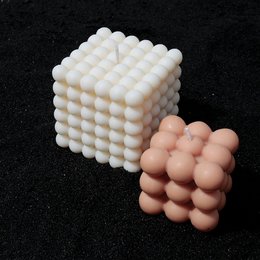 Tall, round, beige wax candle with a bubble-like texture.