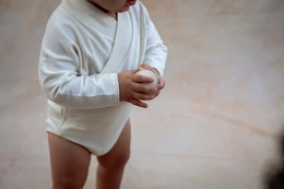  Soft, cozy baby romper in neutral colors like ecru, light brown, dark brown, and light green. Available in sizes 1M, 3M, 6M, 9M, 12M, and 18M.