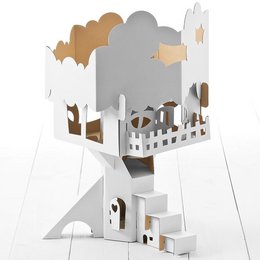 A white and gray wooden tree house with various shapes and cutouts, including clouds, houses, and a fence. The tree house appears to be a decorative or artistic piece, likely intended for display or as a children's toy.