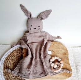 Soft, cuddly sand-colored rabbit plush toy with long ears and a sweet expression, nestled in a woven basket with wooden beads.