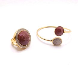 Large pearly gemstone ring with rhodium-sunstone. The ring features a large, round sunstone gemstone set in a gold-tone metal setting. The sunstone has a deep red-orange color with a pearly, iridescent finish.