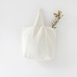 Large white linen shopping bag with wooden handles.