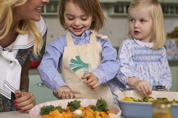 A colorful cooking apron worn by young children as they prepare a meal together in the kitchen. The apron features a playful design and the children appear engaged in the cooking activity.