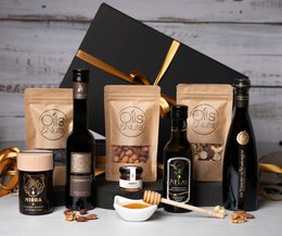 A gift box containing a variety of cooking oils, honey, and nuts. The box includes glass bottles, jars, and other packaging in a rustic, natural style.