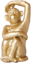 A golden statue of a sitting monkey, with a playful and whimsical expression. The statue has a smooth, shiny surface and appears to be made of a metallic material.