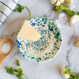  A round, multicolored grater with a speckled pattern of green, blue, and white. The grater appears to be made of ceramic or porcelain material.