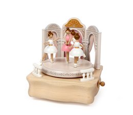 A white and gold music box with a ballerina figurine and two other young dancers performing on a stage.