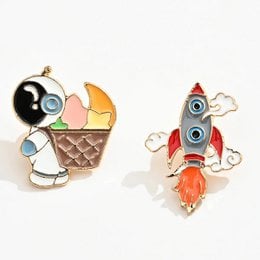 Two enamel pins featuring astronaut with ice cream and red rocket ship, space theme brooches.