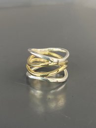 A statement ring featuring a wave-like design in a combination of silver and brass metals.