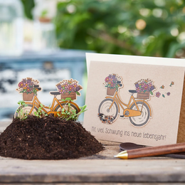 A whimsical birthday card featuring a bicycle with flower pots on the back, conveying a message of new beginnings and momentum into the new year of life.