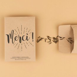 A card with the French word "Merci" (meaning "Thank you") printed on it, accompanied by a decorative design of leaves or branches. The card appears to be made of cardboard or a similar material, suggesting it is a thank you card or greeting card.