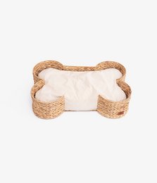 Woven pet basket in the shape of a bone with a soft white cushion for pets.