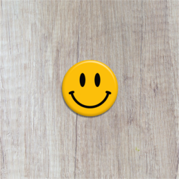 Bright yellow smiley face button brooch with a cheerful expression.