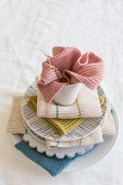 A pink and striped knitted dishcloth made of cotton. The dishcloth has a soft, textured surface and is suitable for everyday kitchen use.