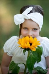 A white headband with a bow for girls. The headband is made of a soft, lightweight material and is designed to keep hair in place during the summer.
