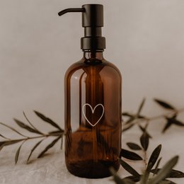 Heart-shaped amber glass soap dispenser with a black pump.