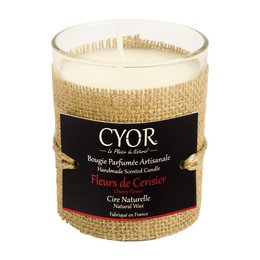 A natural, scented candle with a cherry blossom fragrance, presented in a glass container with a woven texture.