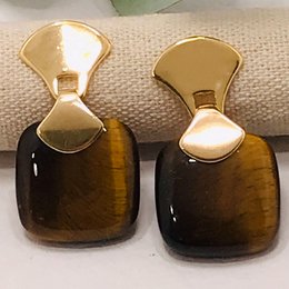 Frameless square gemstone earrings in tiger eye color with a gold-tone metal frame.