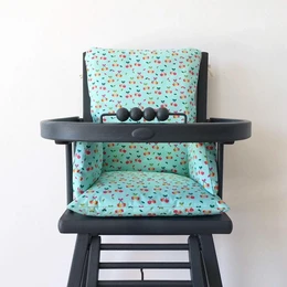 A blue and white high chair cushion with a cherry print pattern, designed for a baby's highchair.