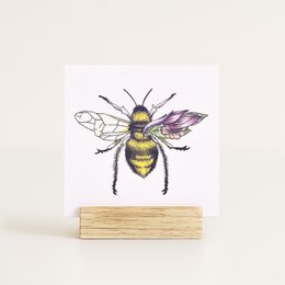 Colorful illustrated postcard featuring a detailed drawing of a bee with vibrant wings and body.