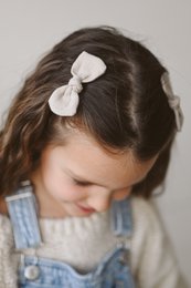 Midi linen hair bows in various colors including bluish grey, white, burgundy red, raspberry pink, dusty pink, beige, deepest black, navy blue, and salmon blush. The bows feature an alligator clip for easy attachment to hair.