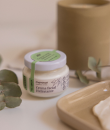 Oily skin face cream in a white jar with a leaf design. The cream is being applied to a woman's face, focusing on the skin and texture.