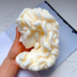 Tall, round, white candle with a textured, wavy surface resembling the Medusa hairstyle.