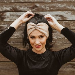 Soft, light brown-beige headband with a bow design, available in small (52-56 cm) and standard (56-60 cm) sizes.