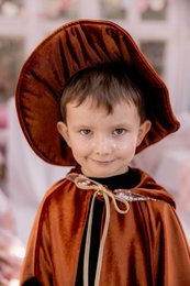 Rust orange velvet witch hat with pointed cone shape, gold trim, adjustable chin strap, magical costume accessory.